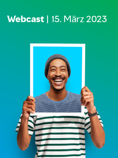 Ein lachender Mann, der eine Mütze trägt und ein Bilderrahmen hält.