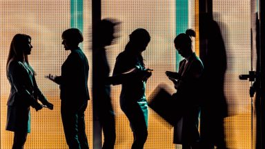 Silhouettes of a group of business people standing or walking in the office building