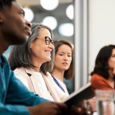 Mujer de negocios sonriente mirando hacia afuera con colegas