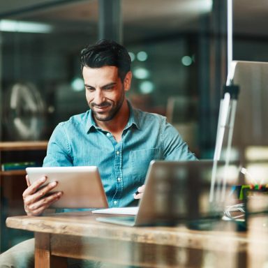 Shot of a young businessman using a digital tablet at his desk in a modern office