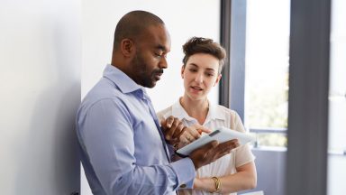 Coworkers standing up and looking at tablet together