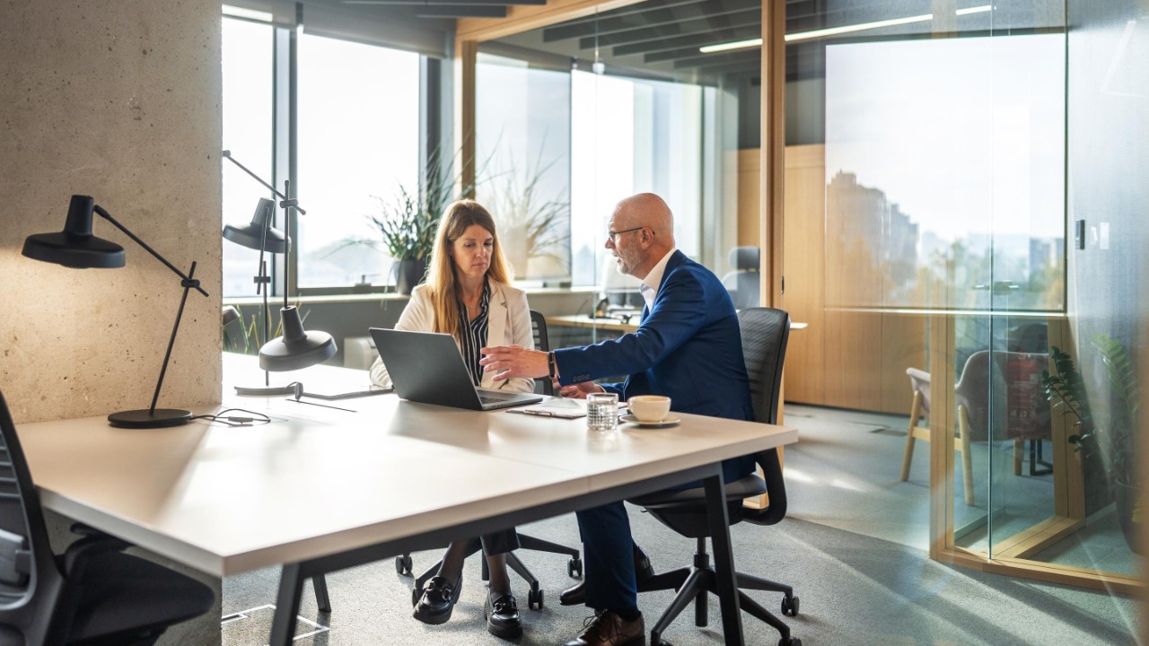 Man and woman having discussion in an open plan office