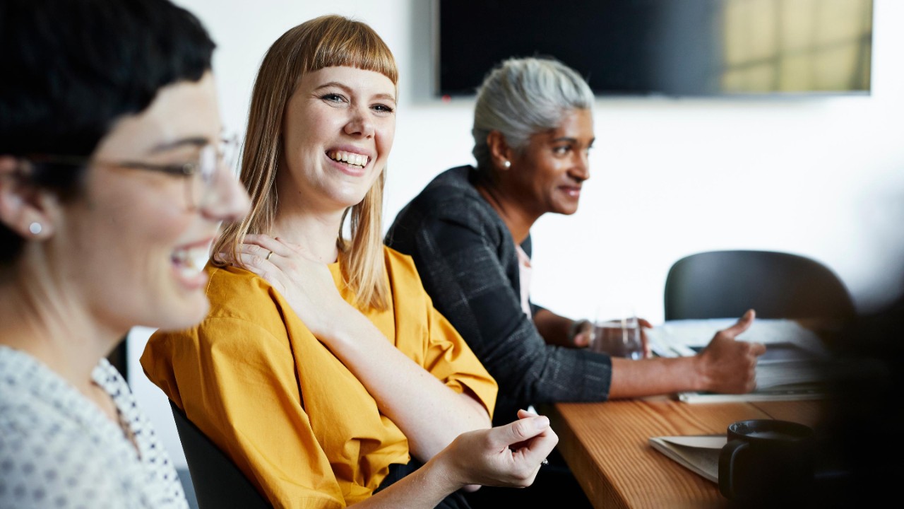 Smiling entrepreneur with female coworker looking away in meeting at workplace