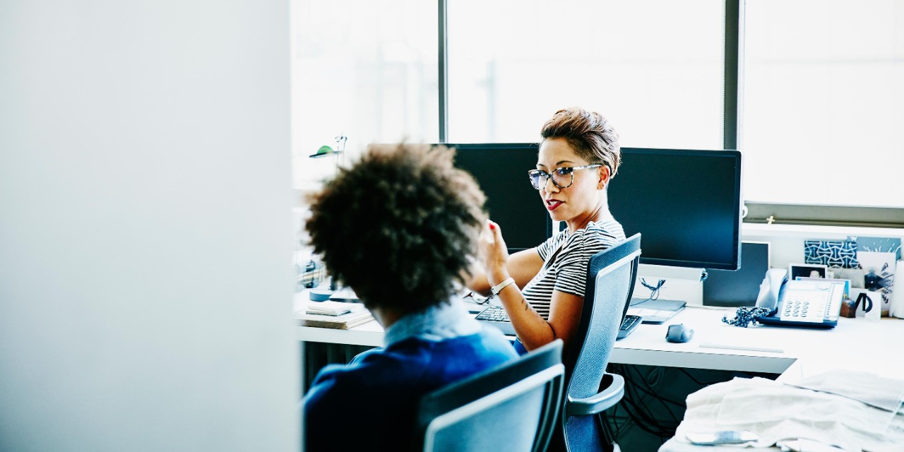 Businesswoman in discussion with businessman at office workstation