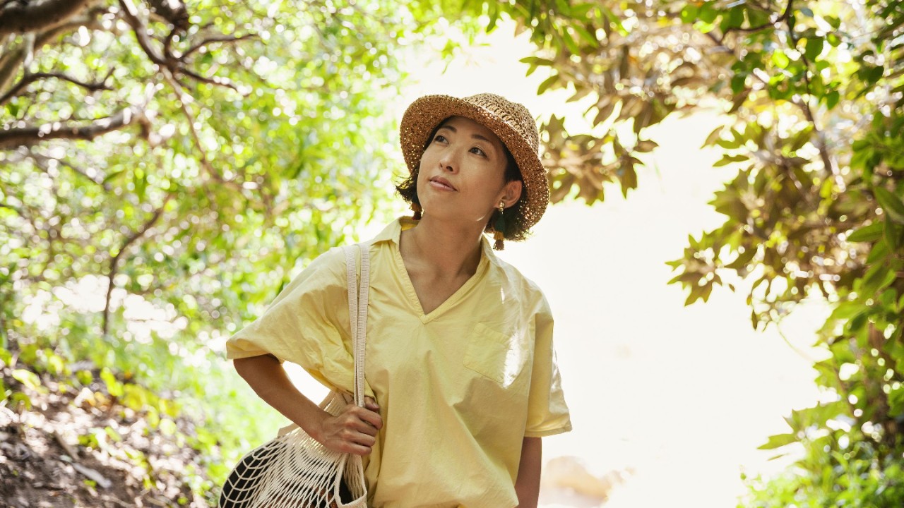Woman in bright yellow shirt walking through a forest