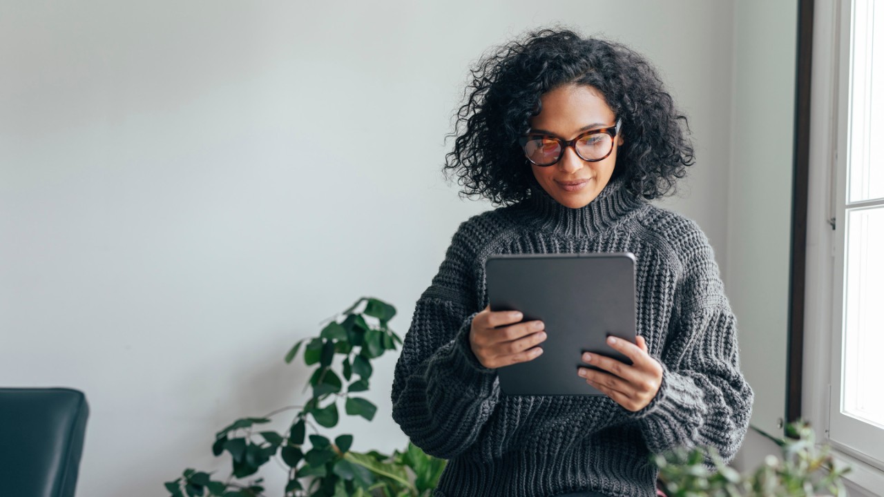 Young woman wearing glasses watching something on her digital tablet (copy space).