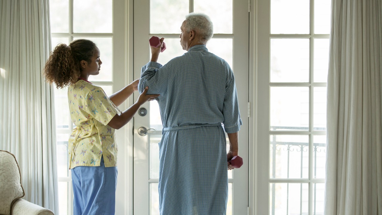 African American nurse helping patient with physical therapy