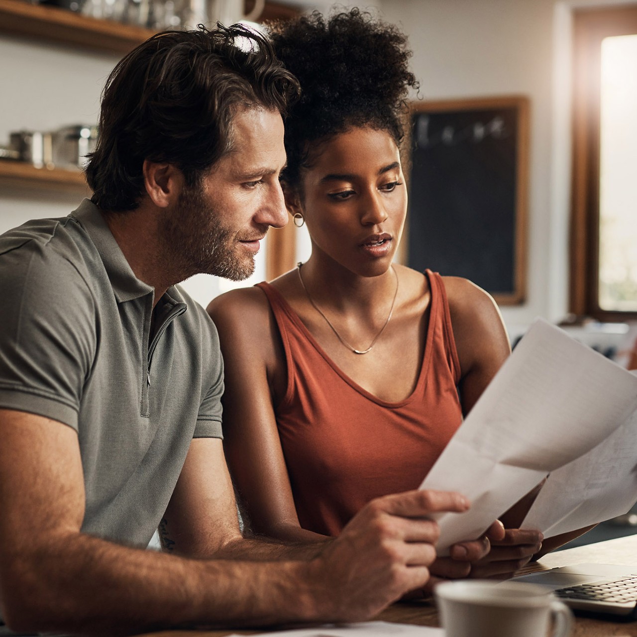 Cropped shot of an affectionate young couple going through paperwork while doing their budget at home
