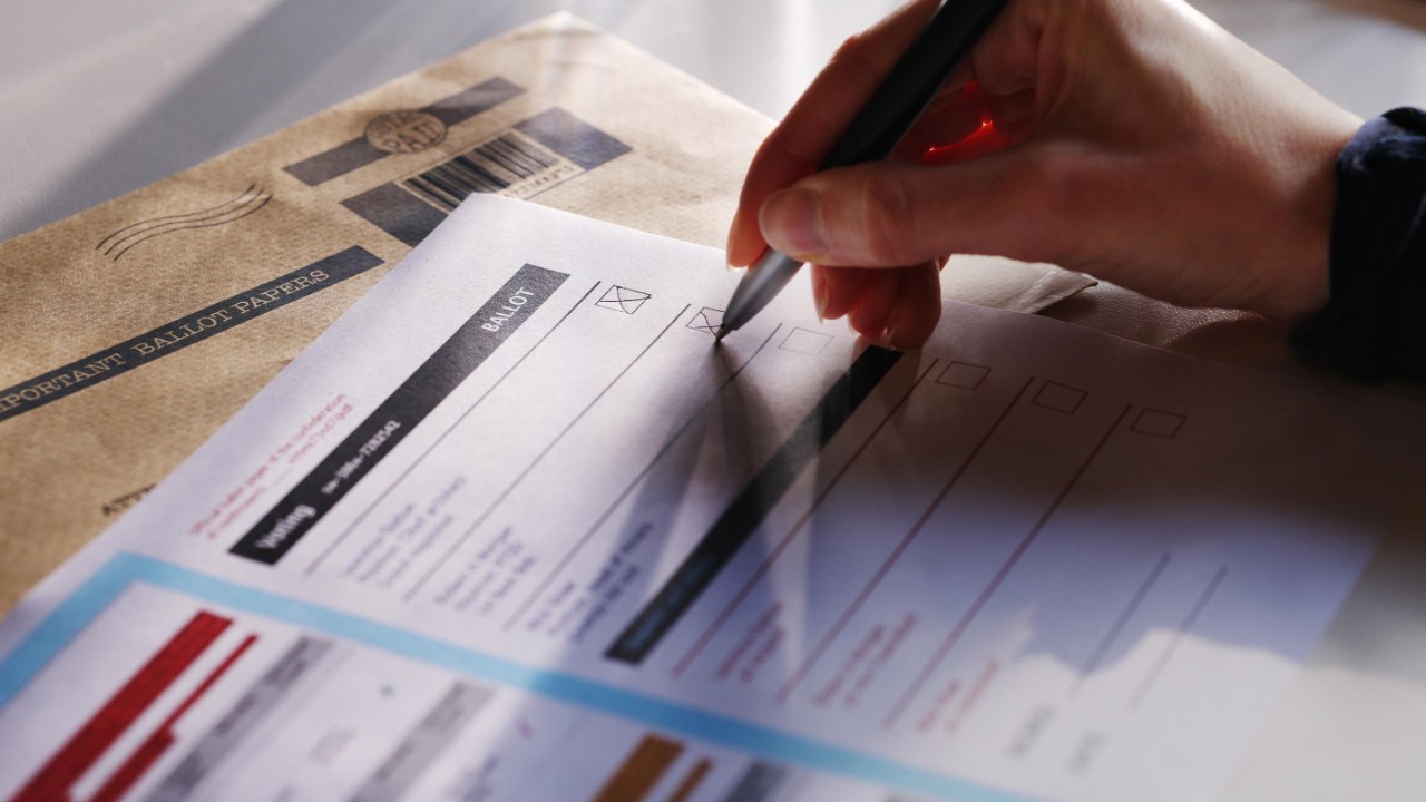 Stock image showing a woman’s hand filling in a postal ballot