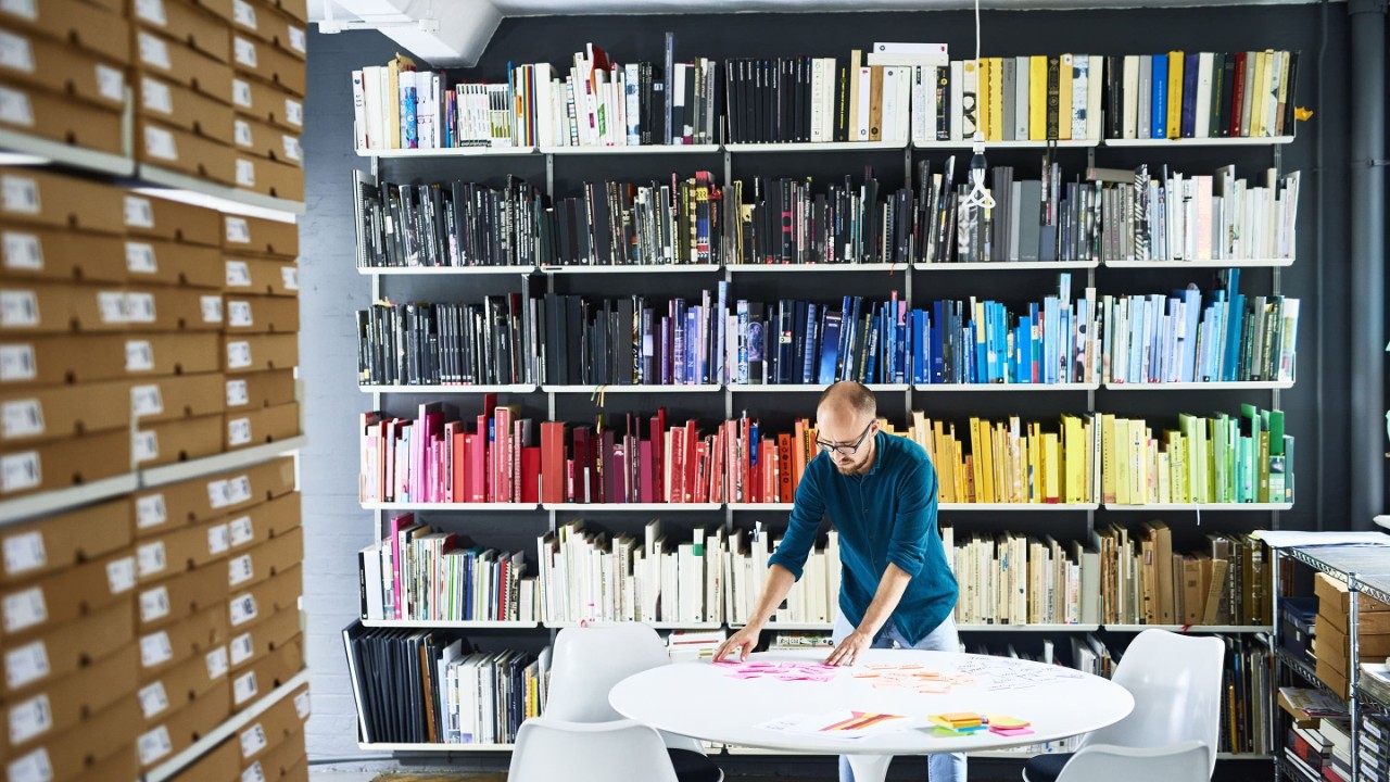 Man working in creative studio in front of colorful bookshelves