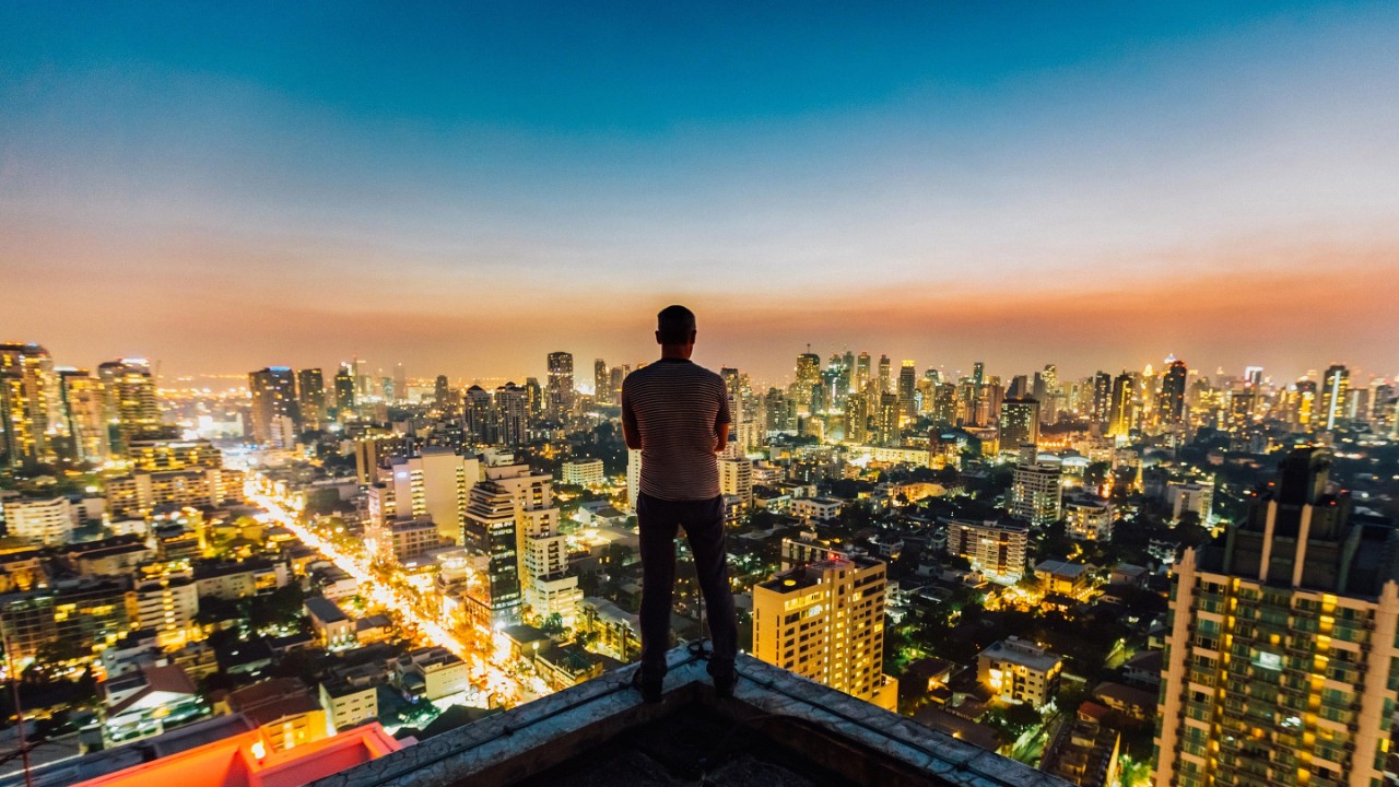 man standing on top of a skyscraper view of the Bangkok city skyline.