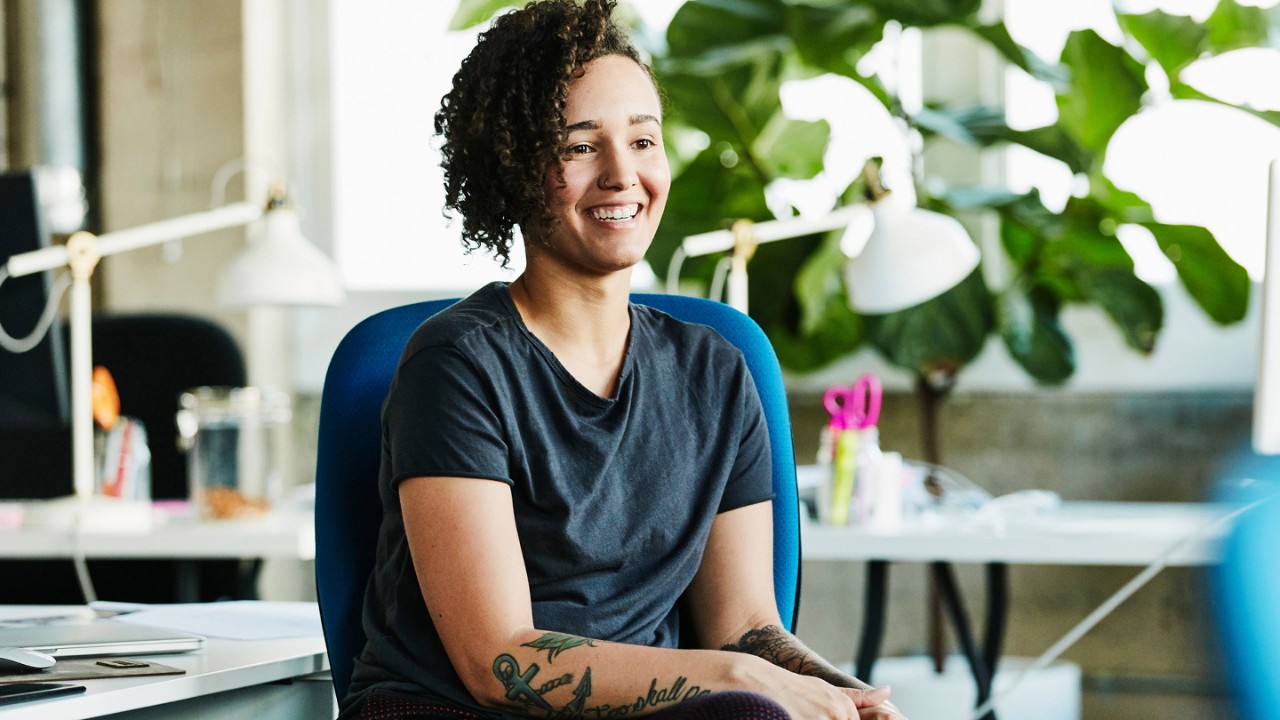 Portrait of smiling businesswoman seated at workstation in design office